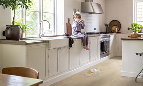 kitchen with a beige timber floor and a kid eating cereals